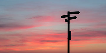 Street signs against a red sunset